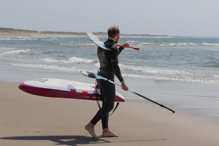 Basti Grimm trägt SUP-Foil Board zum Wasser Bucht Hvide Sande Dänemark