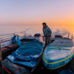 SUP Board aufpumpen auf dem Boot bei Sonnenaufgang auf der Lagune vor Walfishbay.